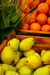 Exotic summer diet. Tropical organic fruit in crate with green leaves. Orange and pear delivery . Autumn harvest. Vertical stock photo.