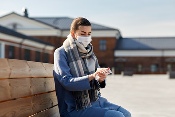 hygiene, health care and safety concept - close up of woman in protective face mask cleaning hands...