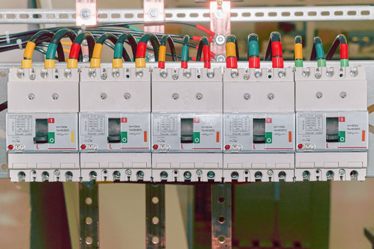 The Number Of High-power Electric Circuit Breakers Molded Case Circuit Breakers In An Electrical Closet. Electrical Cables Or Wires Are Connected To The Switches. The Cables Are Marked With Color.