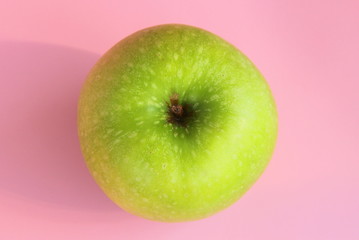Green yellow apple on a pink background. Juicy ripe beautiful fruit.