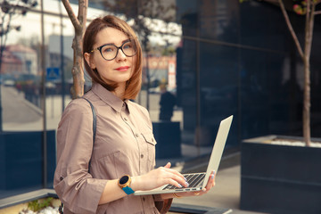 Business woman with computer on the background of a modern building.