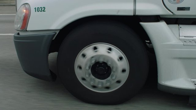 Close up of modern semi-truck front wheel rolling on freeway