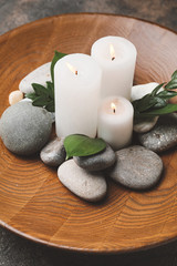 Fototapeta na wymiar Beautiful candles and spa stones on plate