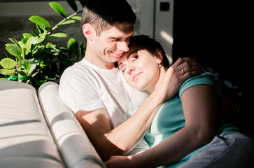 Lovers relax on a cozy sofa in the living room, a woman lies on the man s shoulder, a man and a...