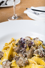 Fresh pappardelle pasta with porcini mushrooms and truffle scent. Parmesan and mozzarella cheese