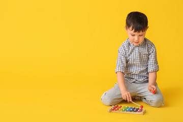 Little boy with toy on color background