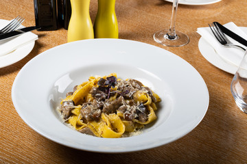 Fresh pappardelle pasta with porcini mushrooms and truffle scent. Parmesan and mozzarella cheese