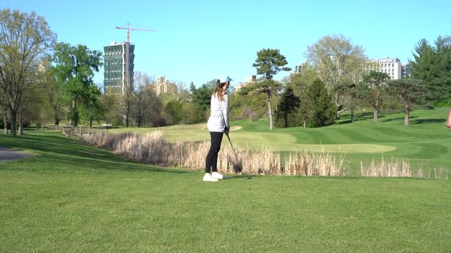 HD footage of woman playing golf on a summer day at a nice golf course.