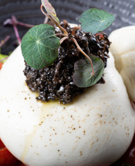 Burrata cheese pouch sack on top of cherry tomatoes salad and rucola arugula leaves, olive paste
