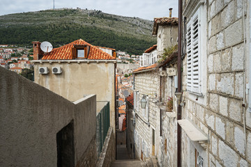 Fototapeta na wymiar Exterior architecture and design of Dubrovnik narrow alley fronting the Adriatic sea, distinctive southern coastal old town, encircled with massive stone walls ans steps- Croatia 