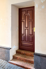 Wooden elegant entrance door with stone red granite threshold and steps at the facade of the...