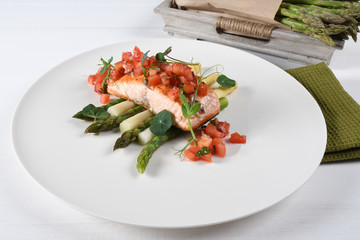 Grilled salmon fillet and white and green fresh asparagus. Healthy eating concept. Chopped tomatoes on top, studio shot