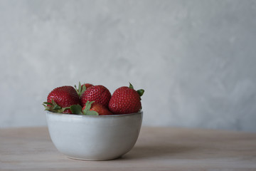 Sweet ripe strawberry in a bowl. Grey background with copy space