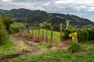 Fototapeta na wymiar Hiking route leading to Deba, with pointers to the town in Basque Country, Spain. Camino de Santiago on a cloudy day.