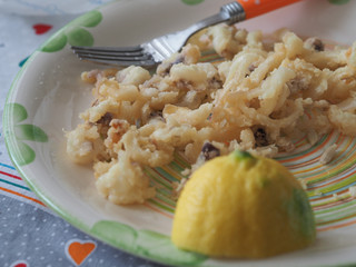 Sunday lunch at home with the family. Second dish based on fried fish with squid and prawns seasoned with lemon served on a colorful plate.