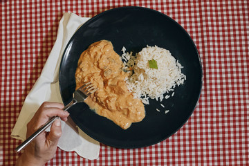 woman eating a plate of chicken and rice in the first person