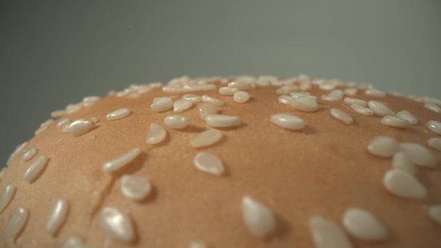 Tasty cheeseburger rotate on the plate. Top side with sesame of just cooked delicious dish. Macro close up shot 4K