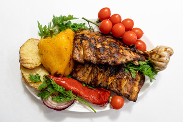 Fried pork ribs with potatoes, potatoes, onions and sprinkled with parsley with pepper in the foreground