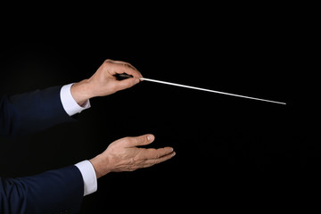 Hands of male conductor on dark background