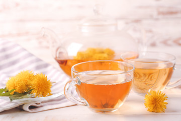 Cup of healthy dandelion tea on white wooden background