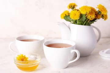 Obraz na płótnie Canvas Cups of healthy dandelion tea with honey on light background