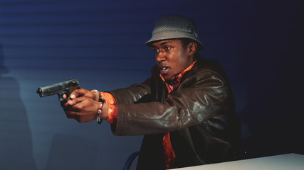 Close-up of black criminal grabbing the gun and threatening to harm cops. He trying to escape from interrogation room.