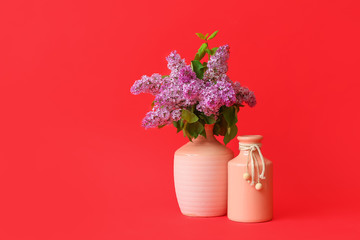 Different vases with bouquet of flowers on color background