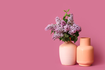 Different vases with bouquet of flowers on color background