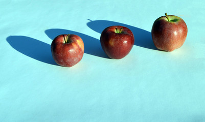 
three apples lie on the table playing with their shadows