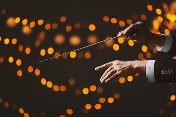 Hands of male conductor on dark background with defocused lights - obrazy, fototapety, plakaty