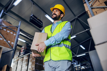 Young attractive supervisor relocating box in warehouse.