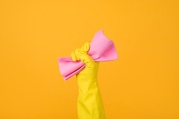 Cropped close-up photo of a hand in yellow glove holding a pink rubber for dusting isolated on yellow background. Housekeeping concept