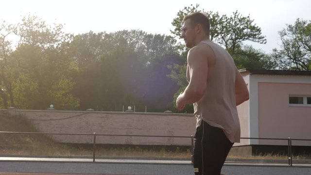 A muscular athlete running a race track at the stadium in the sunset