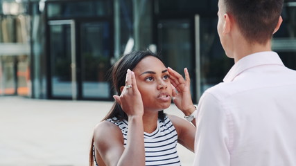 Close-up of mixed-race girl quarreling with her boyfriend outdoors and then leaving him alone. Couple quarrel at a date.