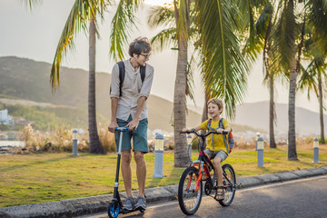 Obraz premium Active school kid boy and his father riding a bike with backpack on sunny day. Happy child biking on way to school. Safe way for kids outdoors to school