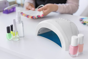 Bottles with cosmetics and lamp for drying gel nail polish in beauty salon