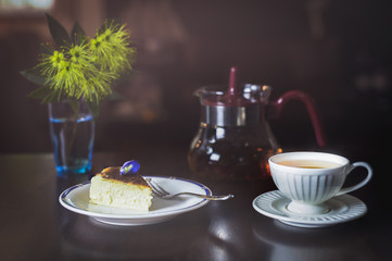 Teatime with slice of basque burnt cheesecake and cup of tea on table.