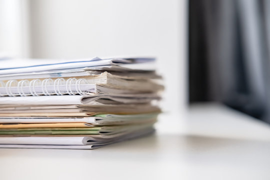 Stack of different notebooks on a white windowsill, in natural light from a window.