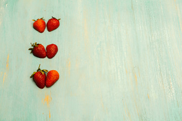 strawberries in form heart, on table blue, conceptual for white.