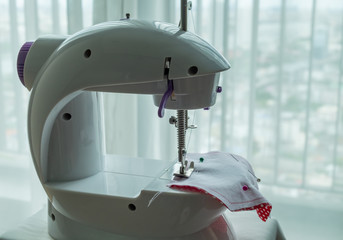 Face mask sewing: Mini sewing machine with a red fabric face mask.