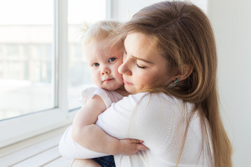 Young mother playing with her baby girl at home. Motherhood, infant and children concept.