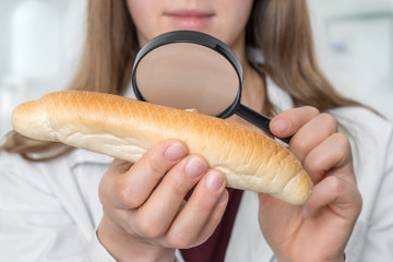Scientist examines a croissant with magnifying glass - obrazy, fototapety, plakaty