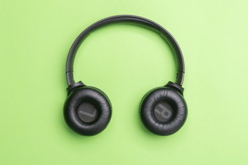 Black headphones oin the center of the photo. From above . Green background. Copy space