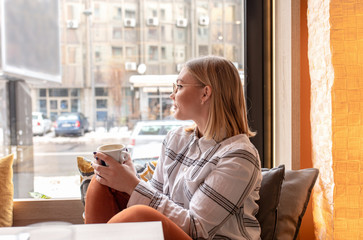 Young woman sitting at the cafe and enjoying cup of coffee.