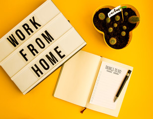 lightbox with text WORK FROM HOME with notebook pen and cactus and TO DO list, copy space on yellow...