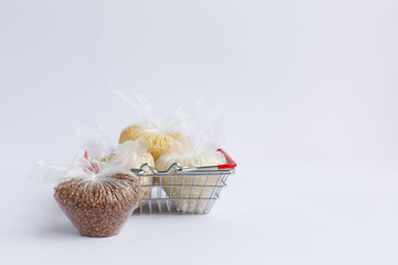 various groats in a grocery basket on a white background