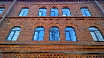 Facade of an old red brick building. Windows with semicircular arches. Cityscape. City living. Real estate