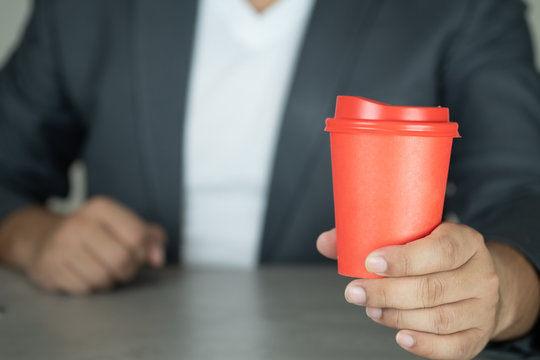 Handsome businessman in suit show red paper cup hot