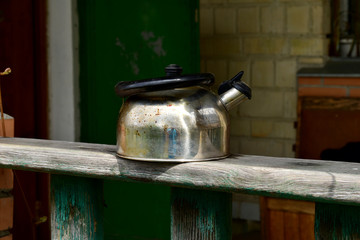 An old metal kettle is standing on the veranda.