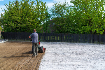 man plows the ground with a motor cultivator. A farmer ploughs the soil using a petrol cultivator.